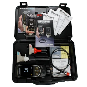 Open instrument case showing PosiTector coating thickness meters, manuals, and cables in a black carrying case with accessories inside.