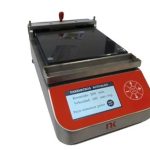 Compact bench-top laboratory device with a red front panel and a small digital display showing current parameters. The metal frame/rails suggest a measuring or testing instrument.